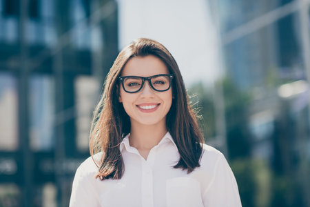Photo of confident shiny young woman wear white formal shirt spectacles smiling outdoorsの写真素材