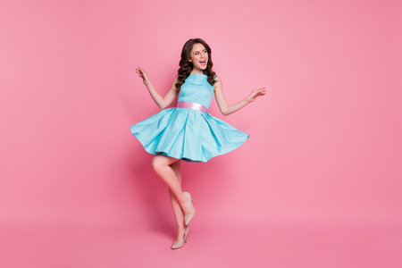 Full length photo of attractive curly lady glamorous clothes event night club dancing skirt flying wear blue teal dress high-heels isolated pastel pink color backgroundの写真素材