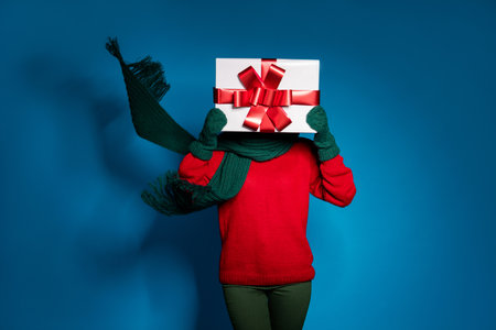 Portrait of incognito girl holding in hands gift box closing face address delivery courier home order Valentine day wind blow kerchief isolated bright vivid shine vibrant blue color backgroundの写真素材