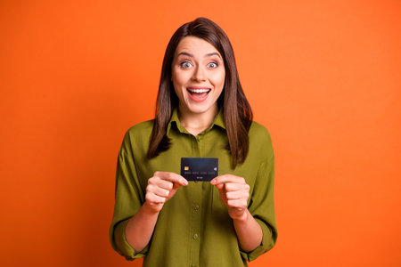 Photo of funky shocked girl hold plastic card look camera open mouth wear green shirt isolated...