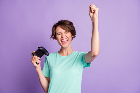 Photo of astonished young lady gamer wear casual teal outfit holding playing console isolated purple color backgroundの写真素材
