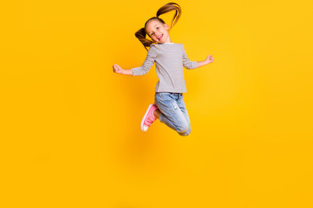 Full size photo of happy positive little girl child kid jump isolated on yellow color backgroundの写真素材
