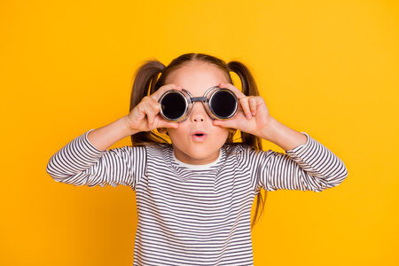 Portrait of young amazed surprised impressed little girl kid child wear funky round sunglasses isolated on yellow color backgroundの写真素材