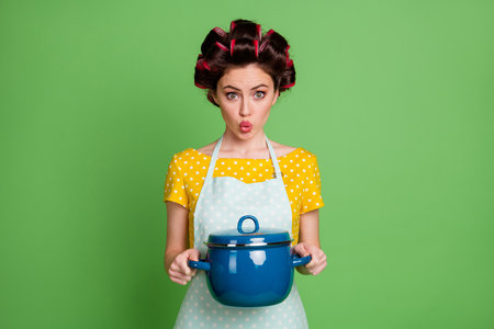 Photo of astonished cute girl hold saucepan soup impressed make lips pouted wear yellow good look clothes isolated over green color backgroundの写真素材