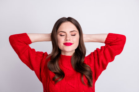 Photo portrait of relaxed chilling girl resting with closed eyes wearing red knitted sweater isolated on pastel grey color backgroundの写真素材