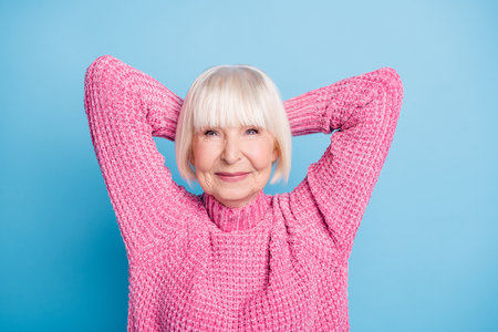 Photo portrait of relaxed woman with two hands behind head isolated on pastel blue colored backgroundの写真素材