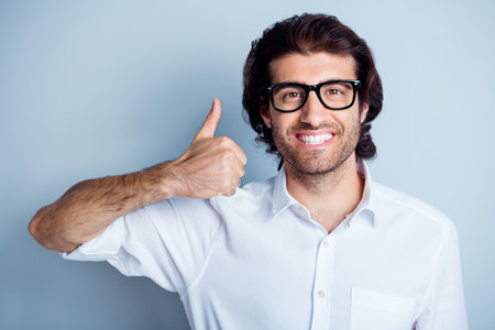 Photo portrait of smiling positive man showing thumb up isolated on clear white colored backgroundの写真素材