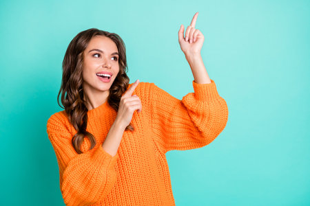 Photo of young attractive girl happy positive smile look show point fingers empty space ad isolated over turquoise color backgroundの写真素材