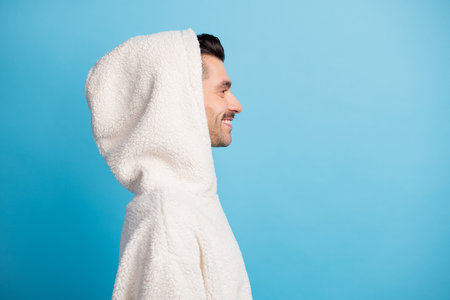 Photo portrait profile of smiling guy wearing wool hood isolated on pastel blue colored backgroundの写真素材