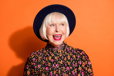 Headshot of sly curious old woman looking blank space smiling red lipstick wearing blouse headwear...