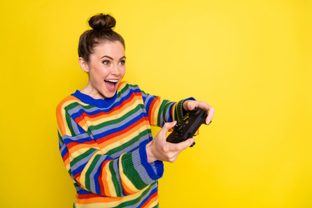 Profile side photo of young attractive woman happy positive smile play video games isolated over yellow color backgroundの写真素材