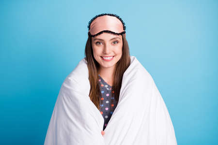 Photo of charming cute young girl comfortably wrapped blanket smiling carefree napping after sport section wear mask dotted shirt pajamas sleepwear isolated blue color backgroundの写真素材