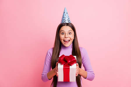 Photo of astonished small kid girl receive gift box wear violet jumper isolated over pastel color backgroundの写真素材