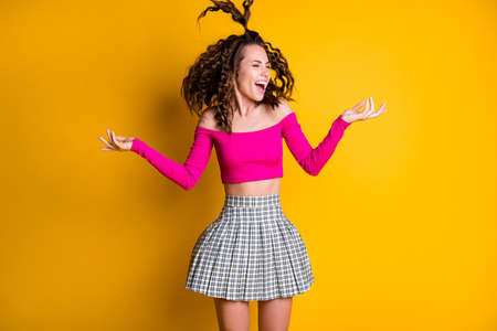 Photo portrait of goofy girl jumping with silly ponytail with raised hands wearing fuchsia crop-top isolated on bright yellow colored backgroundの写真素材