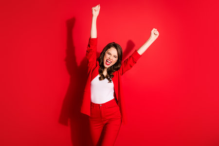 Photo of charming young girl crazy raise two hands knee scream eyes closed wear blazer isolated red color backgroundの写真素材