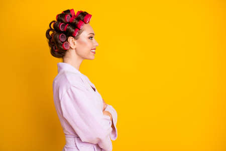 Profile side view portrait of charming cheerful woman wearing curlers folded arms copy space isolated over bright yellow color backgroundの写真素材