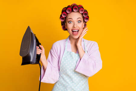 Close-up portrait of pretty amazed glamorous cheerful maid holding in hand cable iron fast isolated on bright orange color backgroundの写真素材