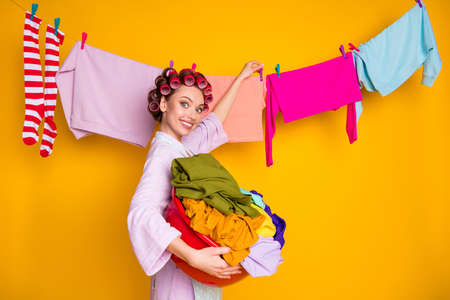 Portrait of glamorous cheerful funky maid hanging washed things isolated bright orange color backgroundの写真素材