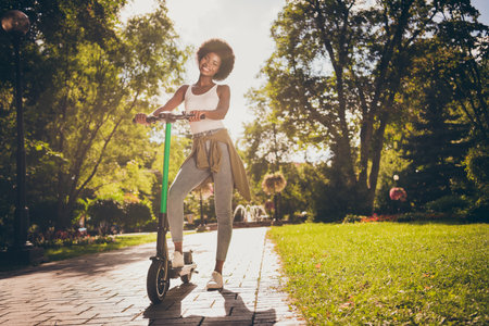 Full length body size view of her she nice-looking attractive slim fit thin cheerful girl riding kick scooter enjoying spending free spare time on fresh air having fun outdoorの写真素材