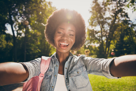 Photo portrait of girl shooting a selfie in sunshine outdoorsの写真素材