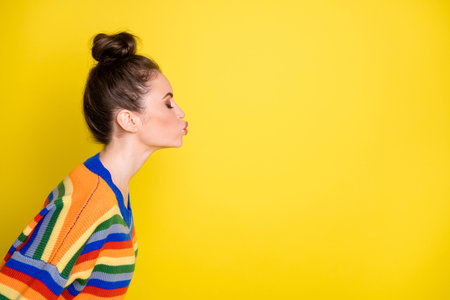 Portrait of adorable lady kiss empty space closed eyes wear sweater isolated on vibrant yellow color backgroundの写真素材