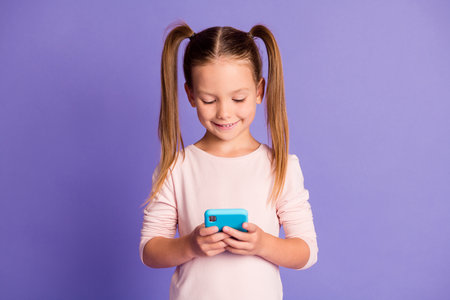 Photo of beautiful pretty little girl look hold phone addicted user wear pullover isolated on violet...