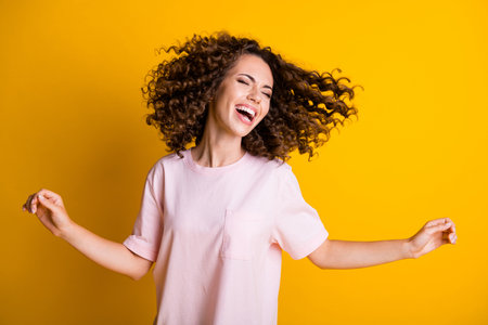 Photo portrait of dancing woman with flying hair isolated on vivid yellow colored background
