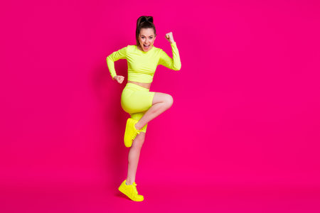Full size profile photo of astonished young lady stand fists up yell dress sport suit sneakers isolated on pink color background.の写真素材