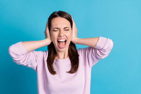 Photo of sad displeased helpless lady close arms ears yelling eyes closed cant stand terrible voice hopeless stressed wear casual purple sweatshirt isolated blue color backgroundの写真素材