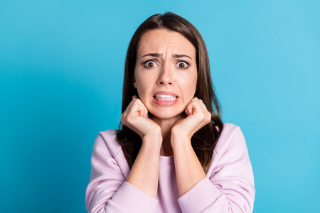 Closeup photo of sad depressed displeased lady hold arms cheekbones horrified facial expression made huge big mistake feel guilty wear casual purple sweatshirt isolated blue color backgroundの写真素材