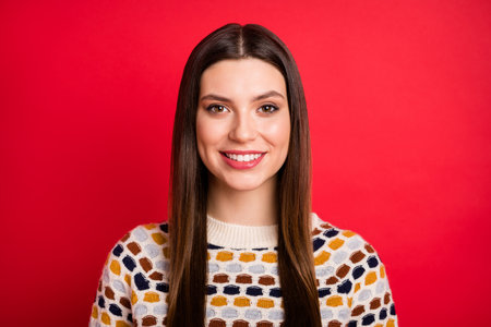 Portrait of optimistic girl wear light sweater isolated on red color backgroundの写真素材