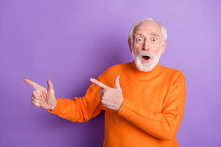Portrait of impressed person direct fingers empty space unbelievable offer open mouth isolated on purple color backgroundの写真素材