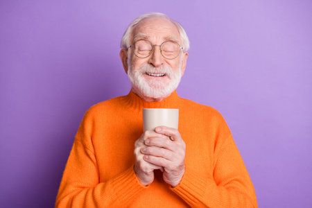 Portrait of cheerful person closed eyes hands hold hot tea mug nice smell isolated on purple color backgroundの写真素材