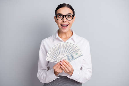 Photo of excited shocked lady hold fan cash open mouth wear eyewear white shirt isolated grey color backgroundの写真素材
