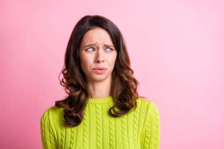 Photo of disgusted anxious girl grimace look side empty space wear green pullover isolated pink color backgroundの写真素材