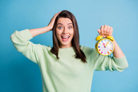 Photo of crazy astonished girl hold clock touch hand head isolated over blue color backgroundの写真素材