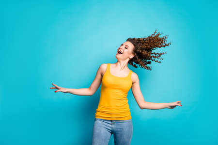 Photo of pretty redhead young girl dancing open mouth wind blow hair wear jeans yellow singlet isolated blue color backgroundの写真素材