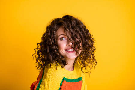 Photo of sweet adorable lady wearing casual colorful sweater looking empty space isolated yellow color backgroundの写真素材