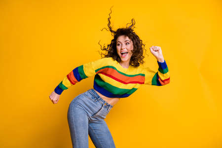 Photo of shiny funny woman dressed casual colorful sweatshirt dancing looking empty space hands arms fists isolated yellow color backgroundの写真素材