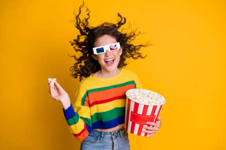 Photo of cheerful funny young lady hold popcorn bucket watch movie wear spectacles striped sweater...