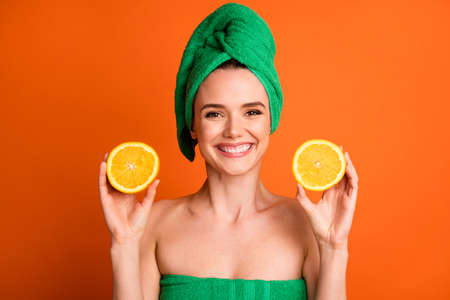 Photo portrait of woman holding two orange citrus slices isolated on vivid orange colored backgroundの写真素材