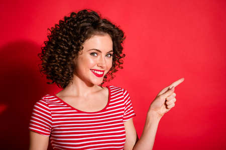 Photo of pretty lovely curly young lady wear casual striped outfit pointing empty space isolated red...