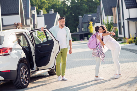 Photo portrait of girl hugging mother coming back from school exiting white car outdoorsの写真素材