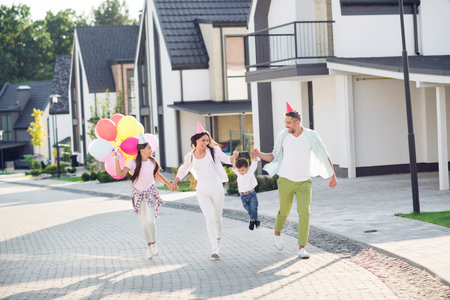 Photo portrait of big family wearing birthday hats headwear lifting boy up outdoors on street in summerの写真素材