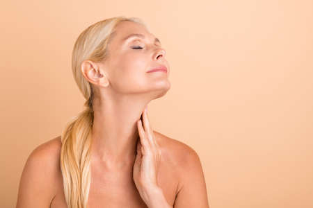 Portrait of calm peaceful middle aged woman touch hand neck enjoy anti pimple procedure isolated...