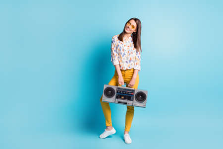 Full length body size photo of brunette keeping retro cassette recorder wearing yellow sunglass isolated on vivid blue color backgroundの写真素材