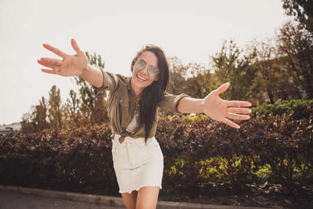 Photo of charming cute girl stretch hands camera want embrace wear brown shirt short skirt park street outsideの写真素材