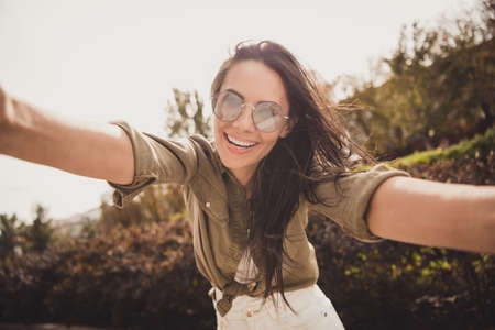 Photo of cheerful pretty girl take selfie having fun shiny smile wear brown shirt spectacles park street outsideの写真素材