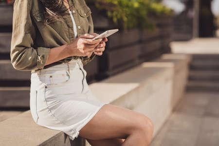 Photo portrait cropped of woman holding phone in two hands texting friends typing using appsの写真素材