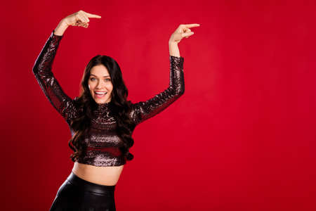 Photo of positive pretty person beaming smile indicate fingers empty space isolated on red color...